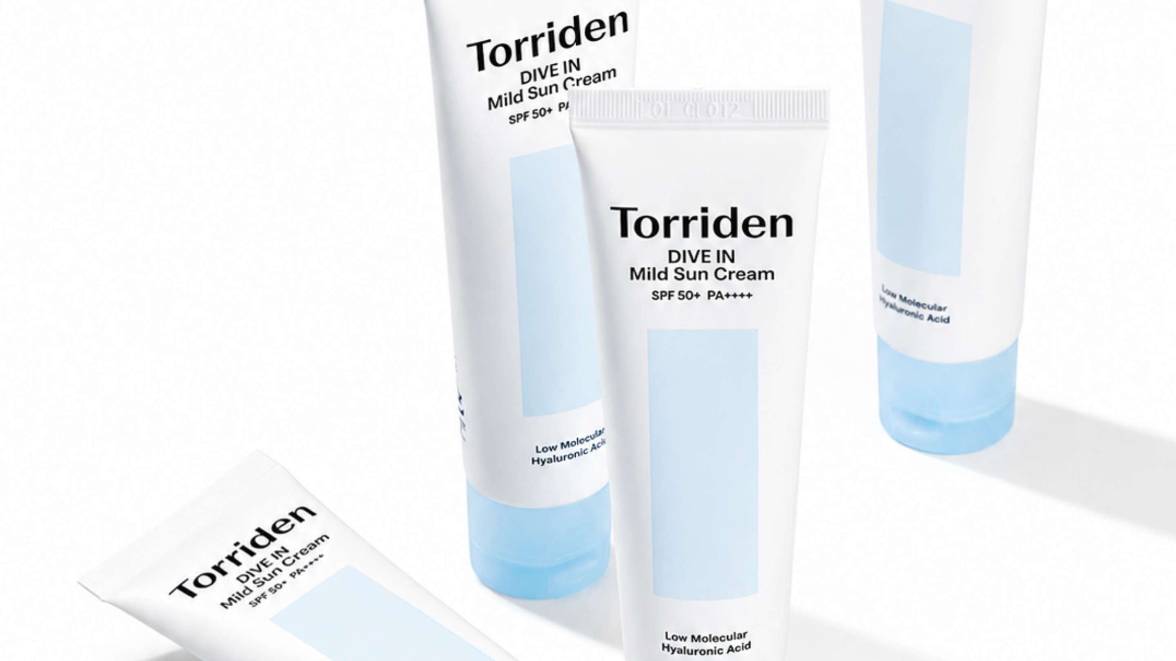En vit tub av PURITO Daily Go-To Sunscreen SPF 50+ PA++++, delvis klämd och liggande på en genomskinlig yta, med kräm som sipprar ut.