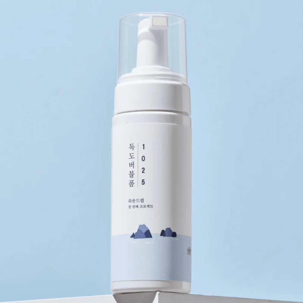  Das Produkt ist ein "1025 Dokdo Bubble Foam" von ROUND LAB, verpackt in einer weißen Pumpflasche mit minimalistischem Design. Es ist für die Tiefenreinigung des Gesichts ohne Reizung vorgesehen.