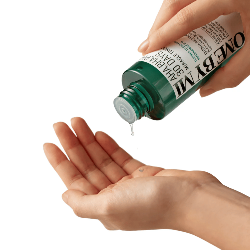 Eine Hand hält eine grüne Flasche mit der Aufschrift "AHA, BHA, PHA 30 Days Miracle Toner" und drückt eine klare Flüssigkeit in die Handfläche der anderen Hand, bereit zur Anwendung.
