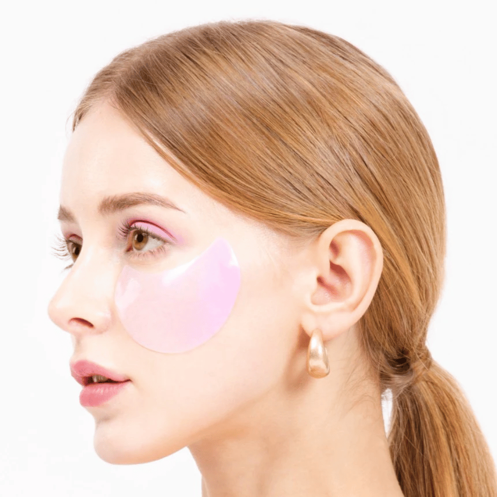 Modell trägt ein rosa Hydrogel-Augenpflaster unter dem Auge, feuchtigkeitsspendend und hautverjüngend.