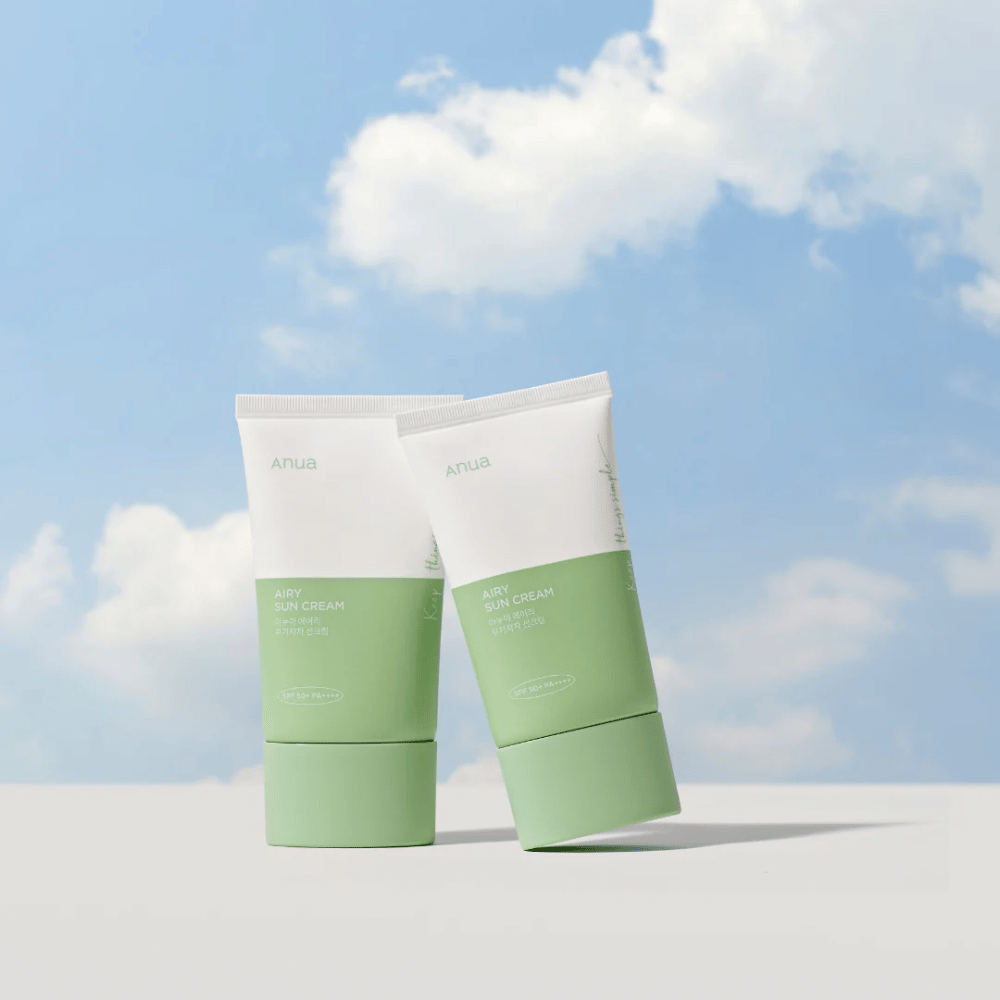 Zwei Tuben von Anua Airy Sun Cream gegen einen Himmel mit weißen Wolken.