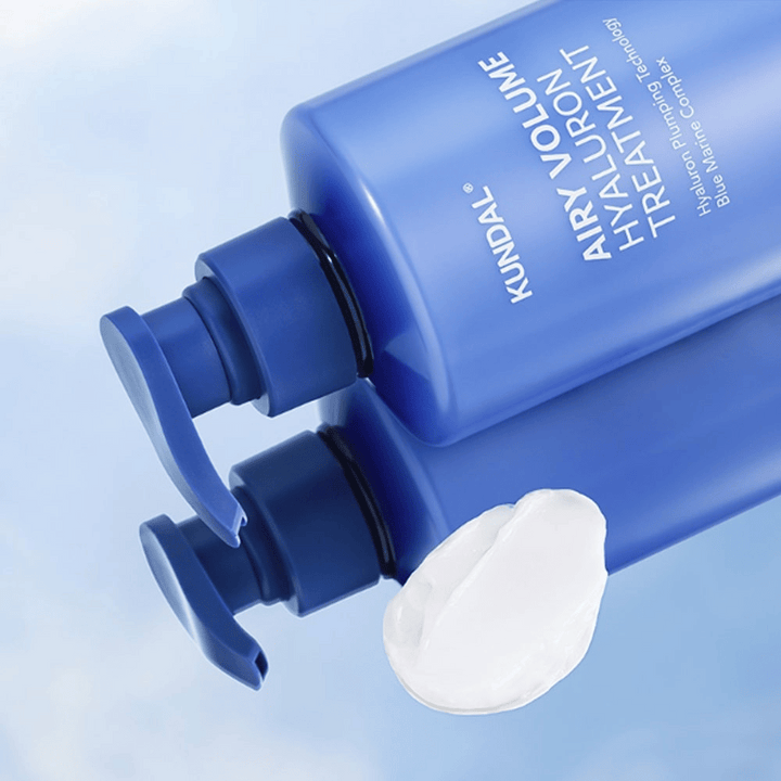 KUNDAL Airy Volume Hyaluron Treatment i blå pumpflaska liggande, med vit krämprodukt synlig bredvid.