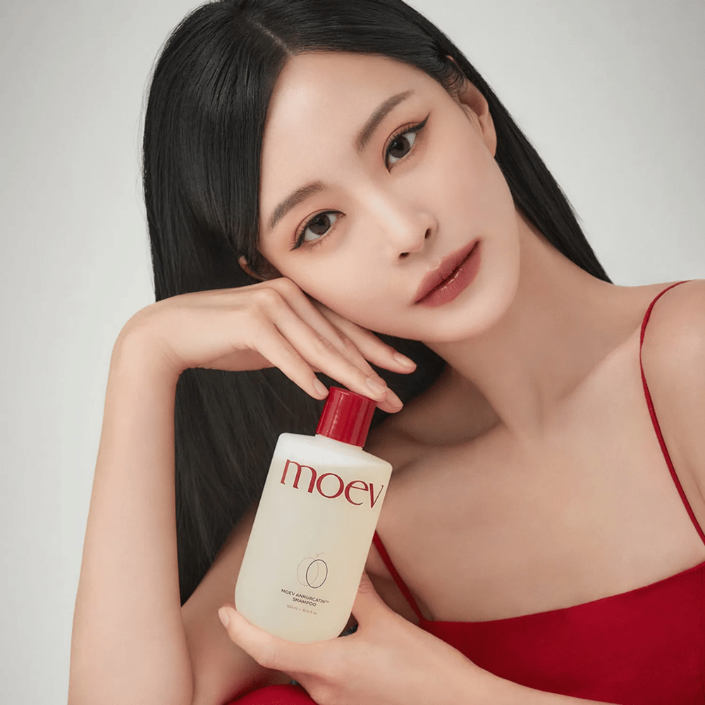 Frau mit langem, glänzendem Haar hält MOEV Annurcatin Shampoo – ein koreanisches Shampoo, das das Haar mit natürlichen Inhaltsstoffen befeuchtet, stärkt und schützt.