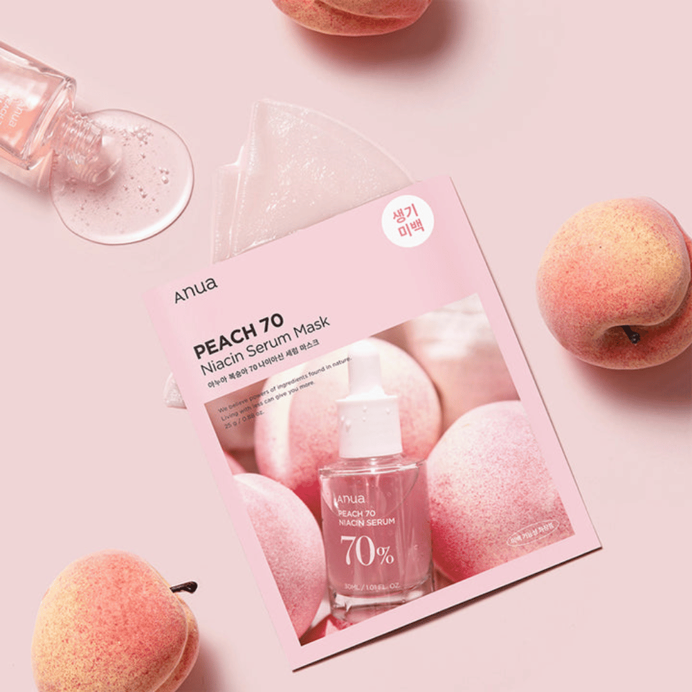 Ein Bild der Anua PEACH 70 Niacin Serum Maske, umgeben von Pfirsichen und einer Flasche Serum. Das Bild hat einen weichen rosa Hintergrund, der die rosa Verpackung ergänzt und das Produkt und die Zutaten hervorhebt.