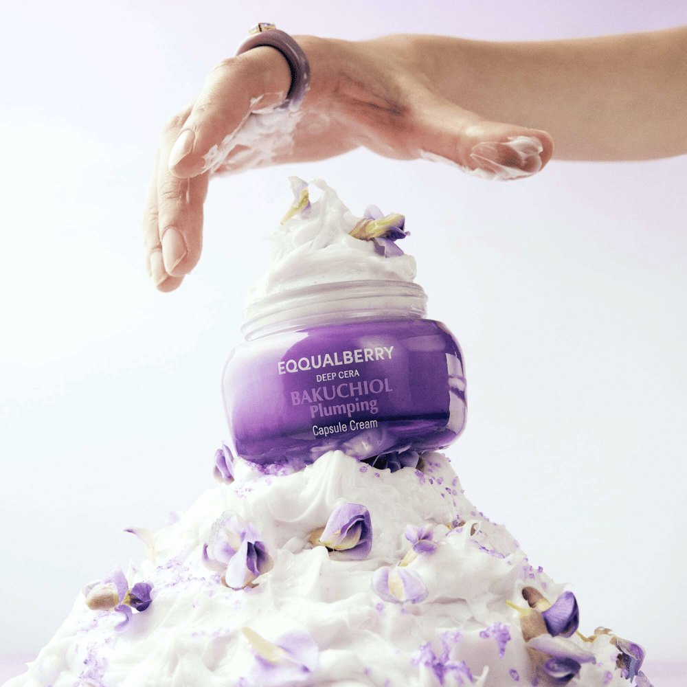 EQQUALBERRY Bakuchiol Plumping Capsule Cream platziert auf einem Haufen von geschlagener Creme mit Blütenblättern – symbolisiert Feuchtigkeit und Pflege.