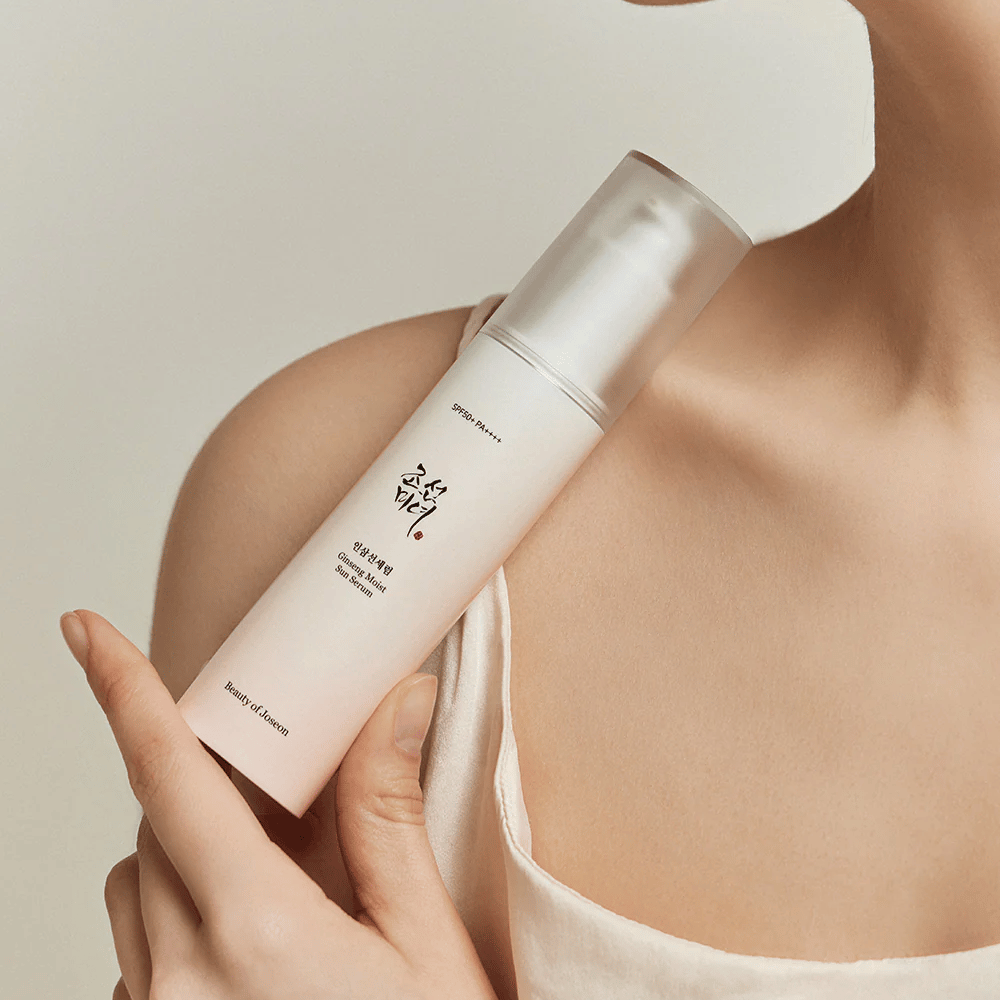 Eine Frau hält eine Flasche von Beauty of Joseon's Ginseng Moist Sun Serum SPF 50+ PA++++, die SPF 50+ PA++++ Schutz und Hautpflegevorteile bietet.