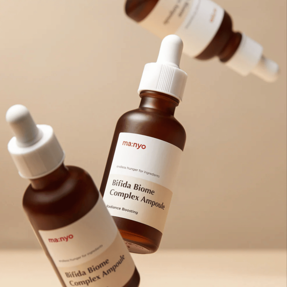 Produktbild mit mehreren schwebenden Flaschen von ma:nyo Bifida Biome Complex Ampoule vor beigem Hintergrund, das ein modernes und minimalistisches Gefühl vermittelt.
