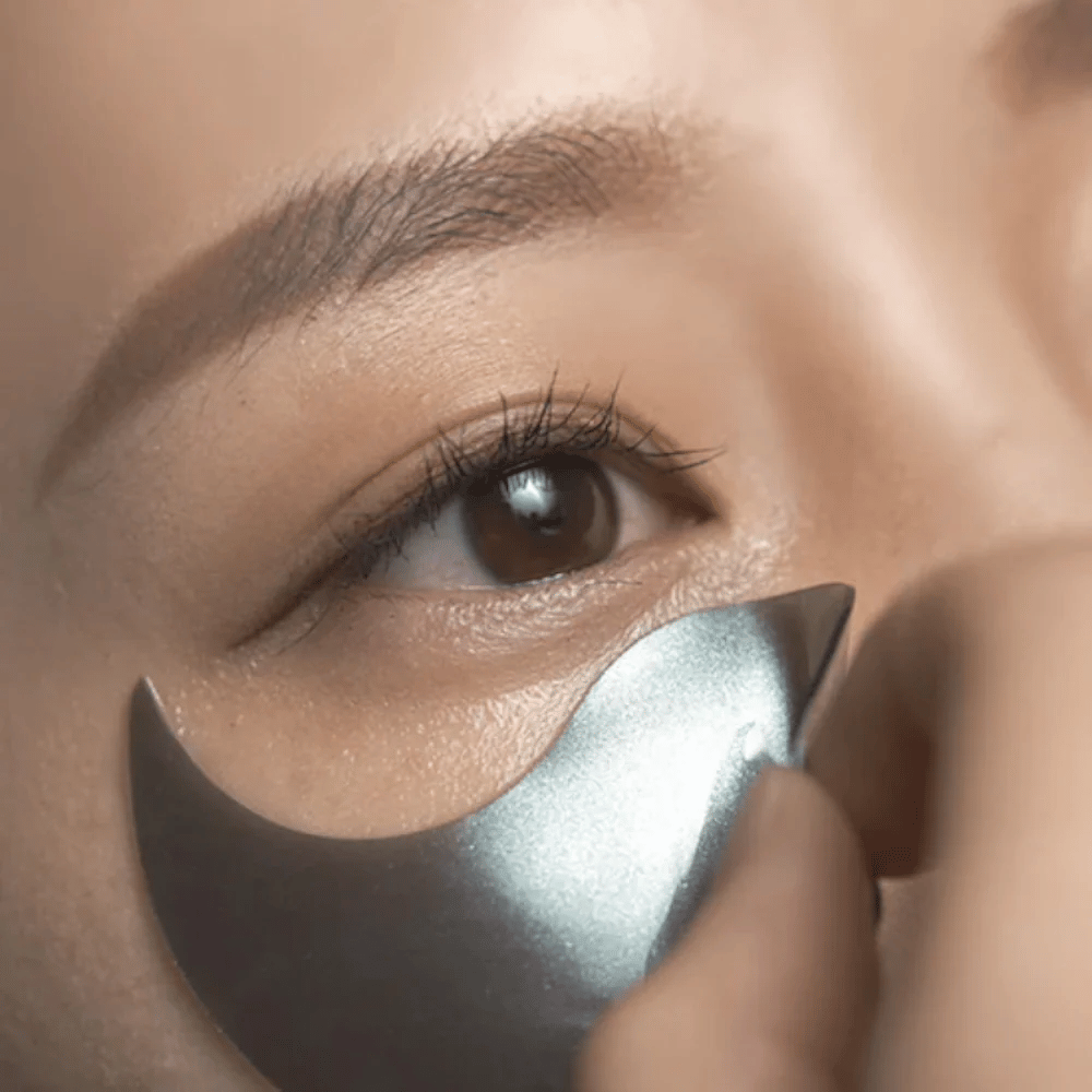 Detailreiches Bild, auf dem ein schwarzes Hydrogel-augenpads unter dem Auge aufgetragen wird. Das Bild zeigt die enge Passform und das kühlende Gefühl rund um die Augenpartie.