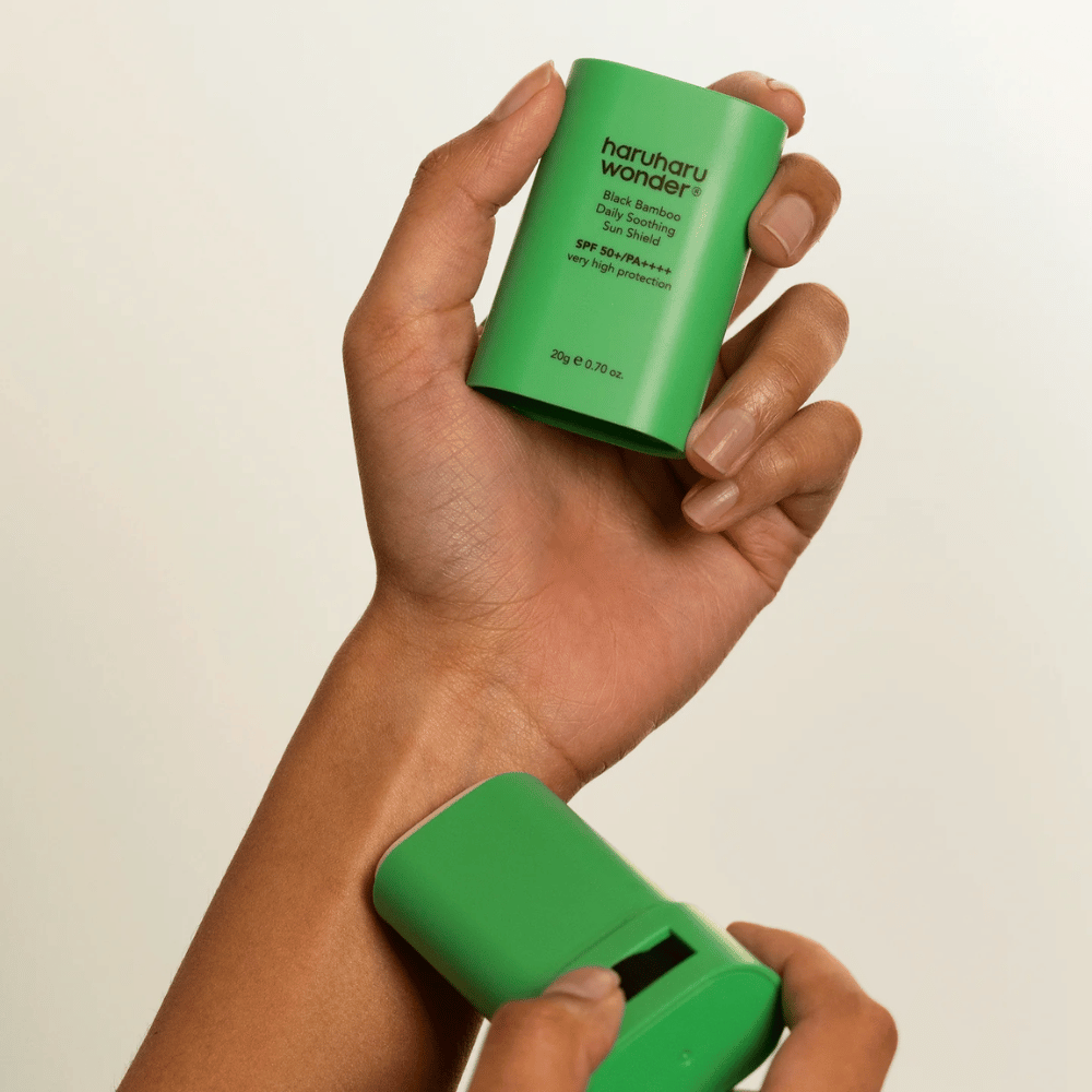 Eine Person trägt Haruharu Wonder Black Bamboo Daily Soothing Sun Shield – einen grünen Sonnenschutzstick mit SPF 50+ PA++++ – auf das Handgelenk auf.