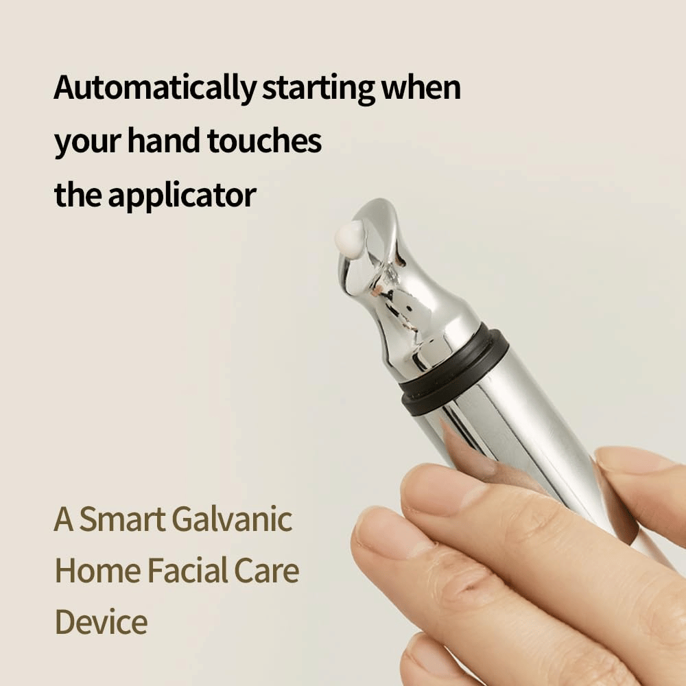 Nahaufnahme einer Hand, die einen galvanischen Applikator für Augencreme mit automatischer Startfunktion bei Berührung hält. Der Text auf dem Bild beschreibt die Funktion und das Gerät als ein smartes Heimwerkzeug für Gesichtspflege.