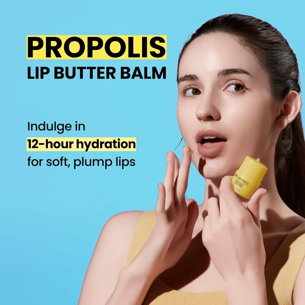 Eine Frau trägt CNP Laboratory Propolis Lip Butter Balm auf, hervorgehoben vor einem blauen Hintergrund. Das Produkt verspricht 12 Stunden Feuchtigkeit für weiche und volle Lippen, was mit einer gelben Tube gezeigt wird, die sie in der Hand hält.