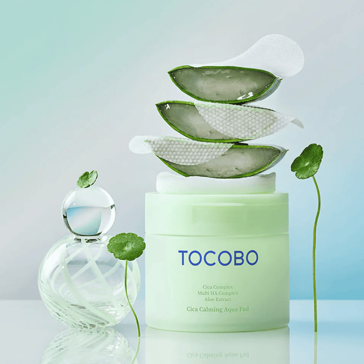 TOCOBO Cica Calming Aqua Pad wird zusammen mit toner pads, Aloe Vera und Centella Asiatica gezeigt. Das Bild hebt die feuchtigkeitsspendenden und beruhigenden Inhaltsstoffe des Produkts hervor.