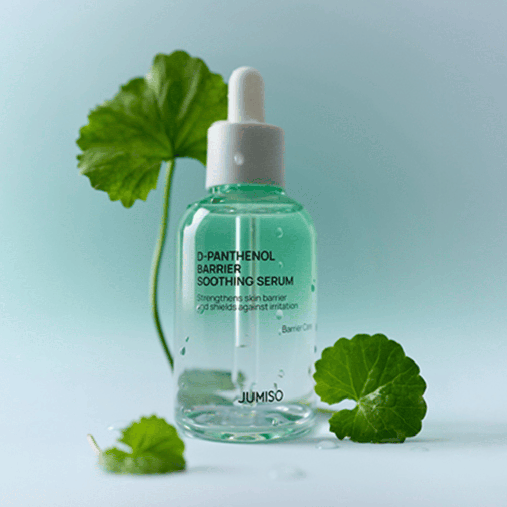 Jumiso D-Panthenol Barrier Soothing Serum i genomskinlig glasflaska med pipett, placerad med gröna blad i bakgrunden.
