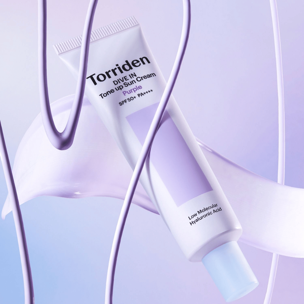 Torriden DIVE IN Tone Up Sun Cream Purple SPF50+ PA++++ präsentiert in einem kreativen Produktsetting mit lila Details, die die feuchtigkeitsspendende Formel hervorheben.