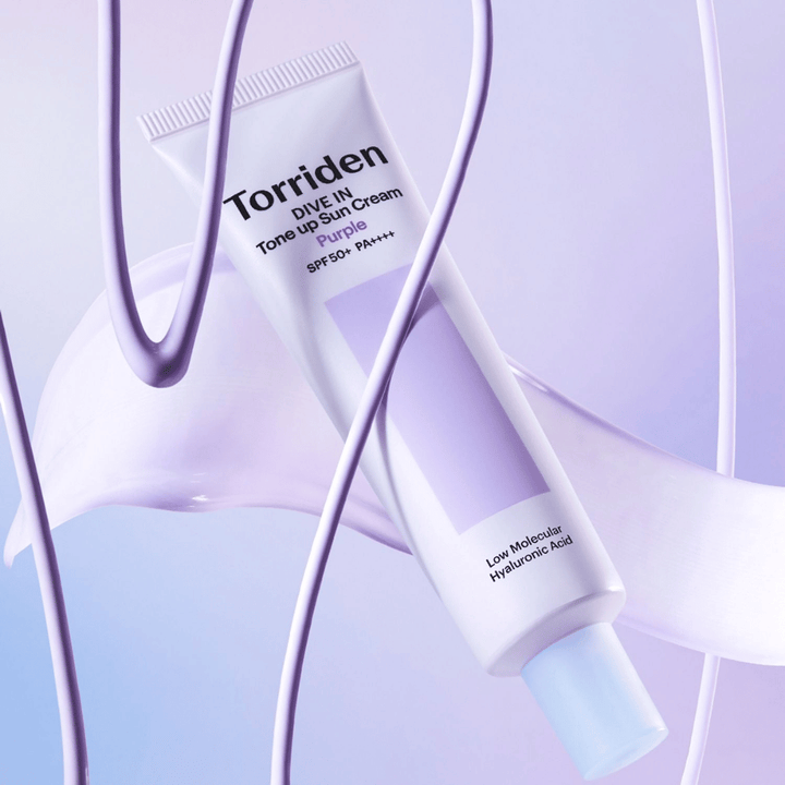 Torriden DIVE IN Tone Up Sun Cream Purple SPF50+ PA++++ präsentiert in einem kreativen Produktsetting mit lila Details, die die feuchtigkeitsspendende Formel hervorheben.