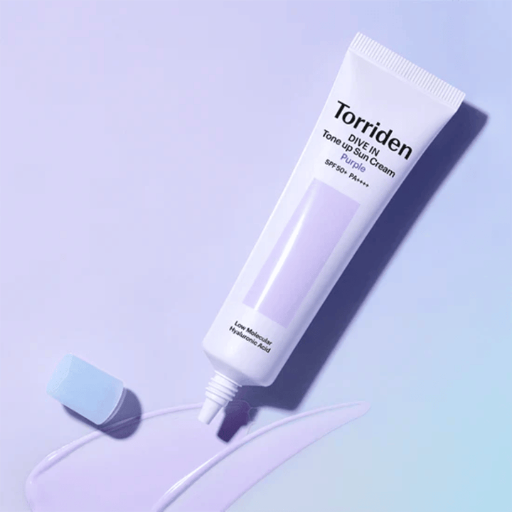 Geöffnete Tube von Torriden DIVE IN Tone Up Sun Cream Purple mit lila getönter Sonnenschutztextur, die die farbkorrigierende Formel des Produkts zeigt.