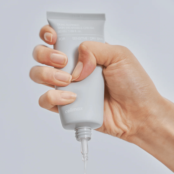 Hand, die Celimax Dual Barrier Skin Wearable Cream aufträgt, barriereverstärkende Gesichtscreme für empfindliche und trockene Haut, die langanhaltende Feuchtigkeit spendet und die Hautbarriere schützt.