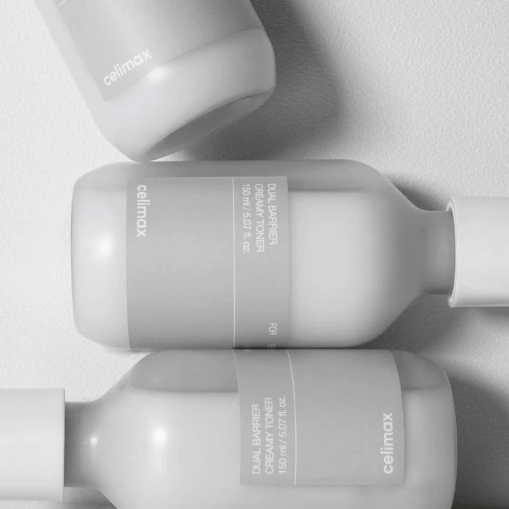 Drei liegende Flaschen von Celimax Dual Barrier Creamy Toner in einem minimalistischen Design mit grauem Etikett und sanftem Licht – perfekt für empfindliche und trockene Haut.