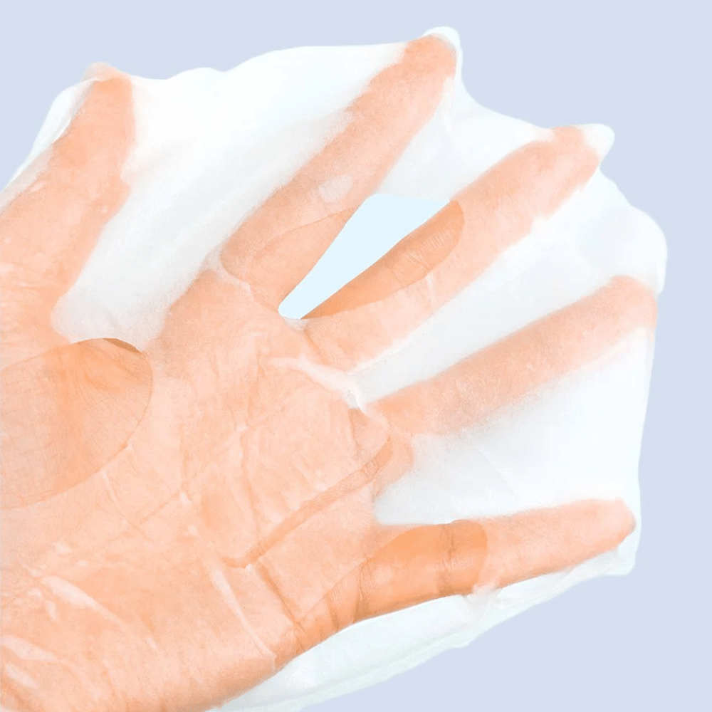 Eine durchsichtige und feuchte Gesichtsmaske wird auf einer Hand vor einem hellblauen Hintergrund gehalten. Die Maske ist so gestaltet, dass sie das Gesicht mit Aussparungen für Augen und Mund bedeckt.