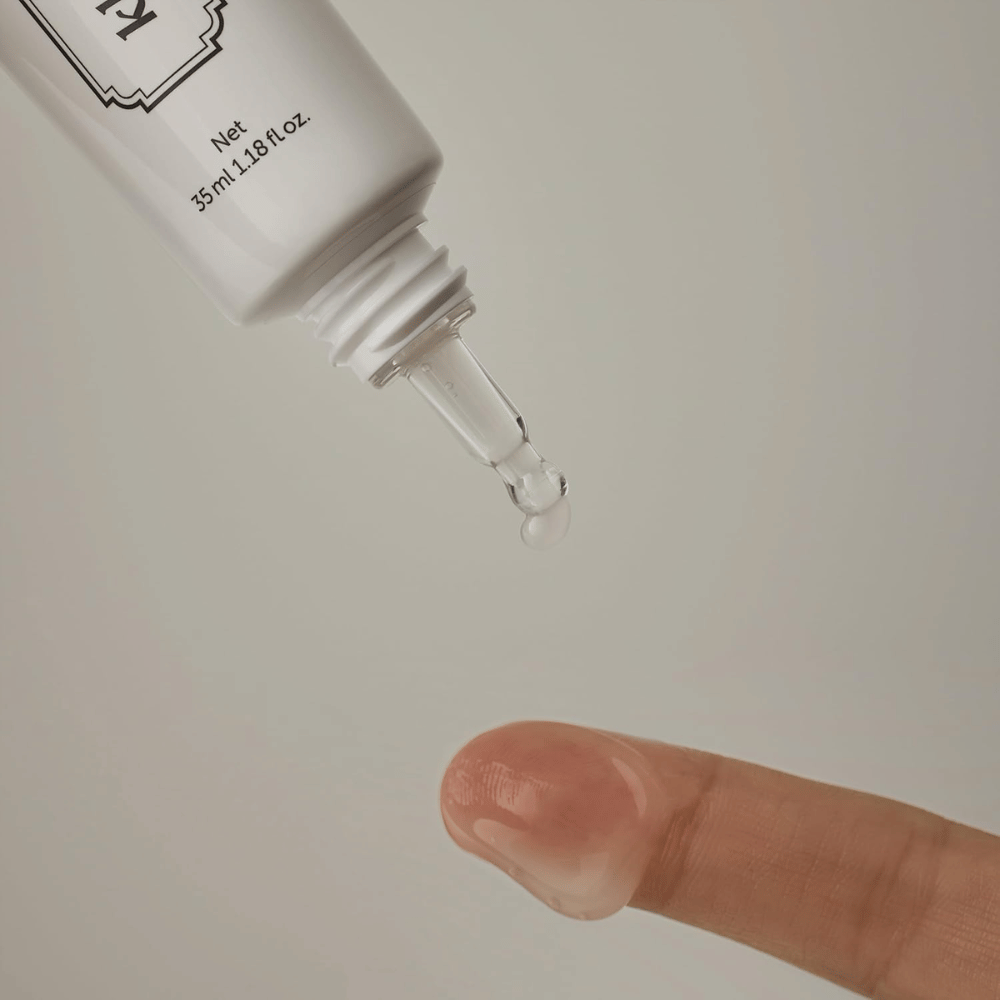 Detailbild, auf dem ein klares, leichtes Gel aus der schmalen Spitze auf einen Finger aufgetragen wird. Das Bild veranschaulicht die transparente, gelbasierte Konsistenz des Produkts und die präzise Anwendung rund um die Augenpartie.