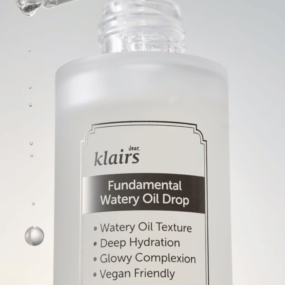 Nahaufnahme der Flasche Klairs Fundamental Watery Oil Drop, mit Text, der die Eigenschaften des Produkts wie "Watery Oil Texture", "Deep Hydration", "Glowy Complexion" und "Vegan Friendly" hervorhebt.