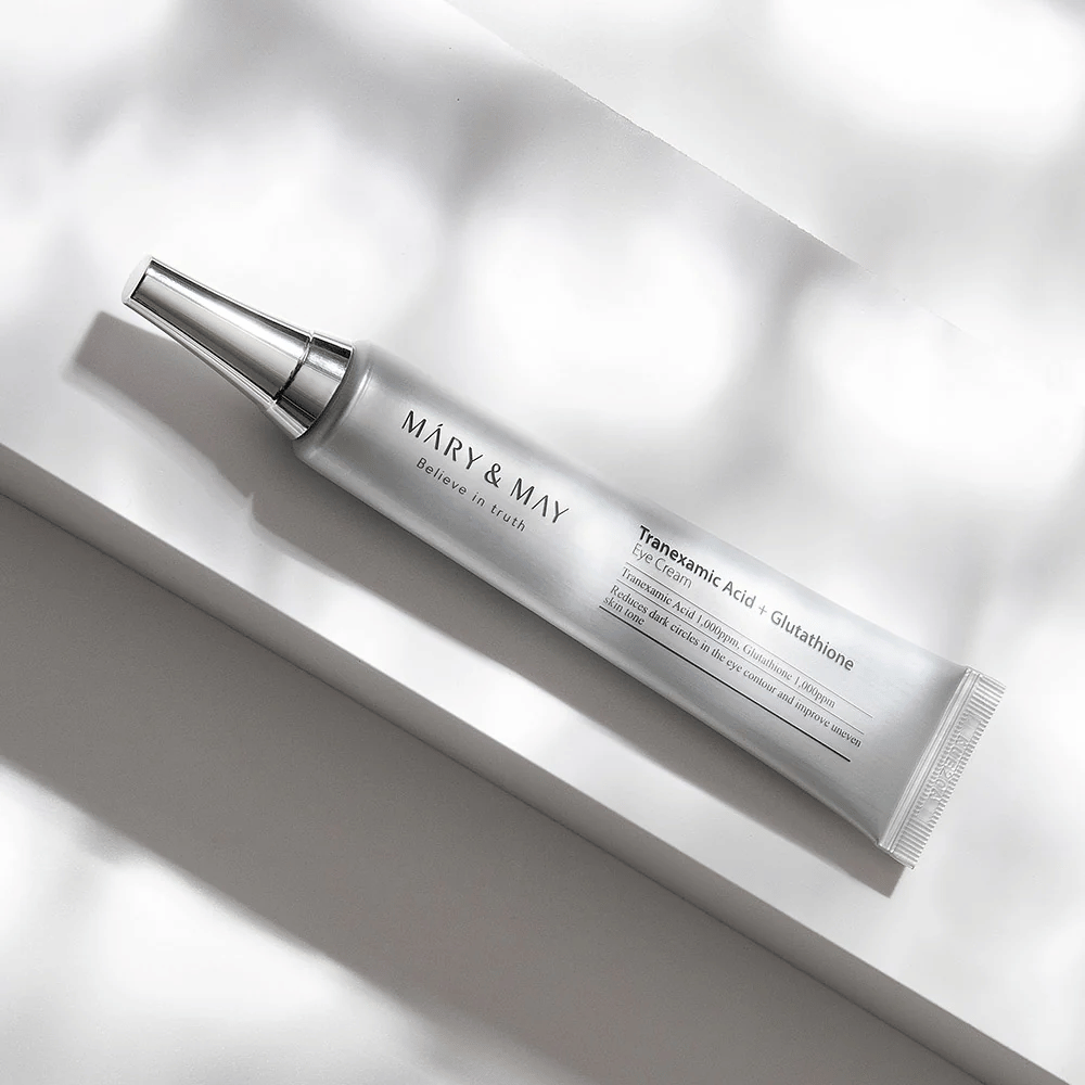 Nahaufnahme von Mary&May Tranexamic Acid + Glutathione Eye Cream mit Metallapplikator, entwickelt, um dunkle Ringe aufzuhellen und den Hautton um die Augen auszugleichen.
