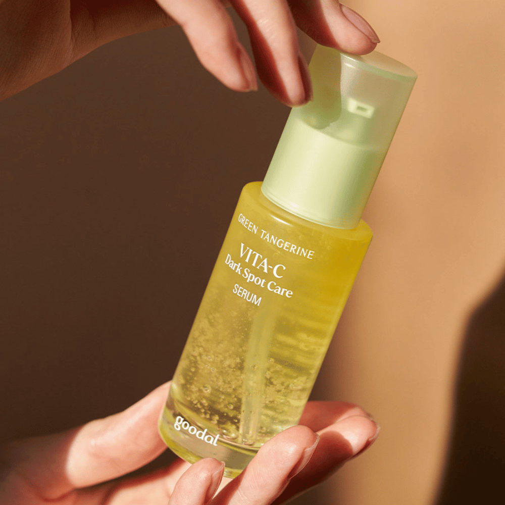 Eine Person, die eine Flasche Green Tangerine Vita C Dark Spot Care Serum 40ml von Goodal für Hyperpigmentierung und Pflege von dunklen Flecken hält.
