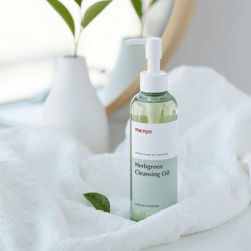 ma:nyo Herbgreen Cleansing Oil in Pumpflasche auf einem weißen Handtuch platziert, beruhigendes Reinigungsöl mit kräuterbasierten Zutaten für sanfte Gesichtsreinigung