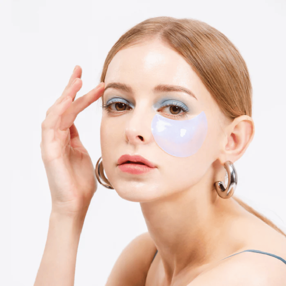 Modell trägt ein blau schimmerndes Hydrogel-Augenpflaster unter dem Auge für erfrischende Wirkung.