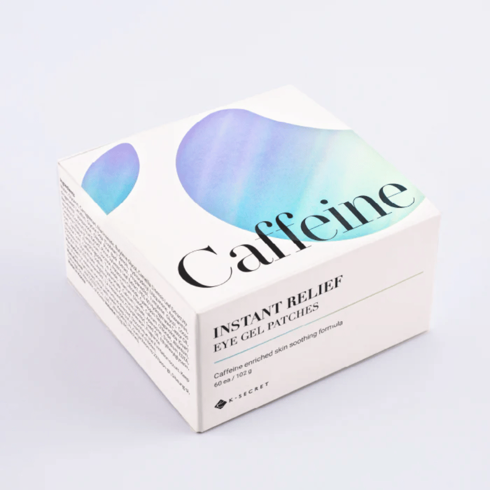 Verpackung von K-Secret Instant Relief Eye Gel Patches mit Koffein im weißen Design mit blauen und grünen Tönen.