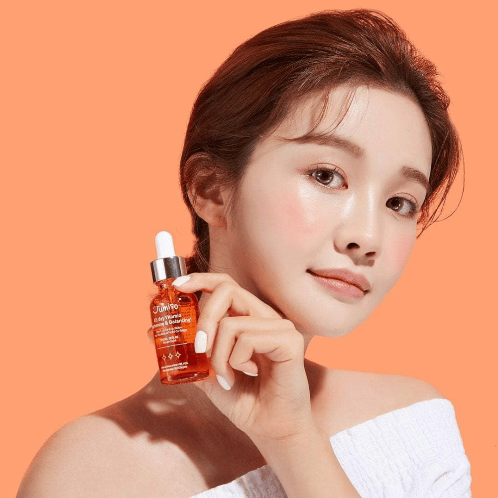 Eine Frau, die eine Flasche JUMISO All Day Vitamin Brightening & Balancing Facial Serum 30ml hält.