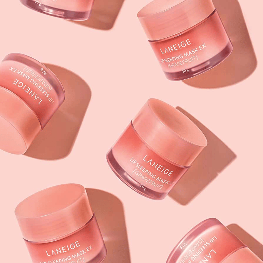Vier Dosen LANEIGE Lip Sleeping Mask Grapefruit 20g auf rosa Hintergrund, fördert Grapefruit und Feuchtigkeit.