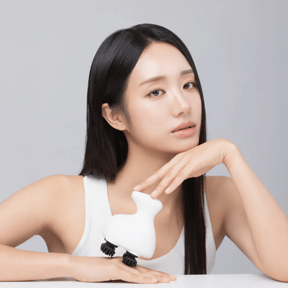 Ein Modell posiert mit Beaund Lift Head Spa und zeigt das ergonomische Design. Das Bild hebt das Produkt als Werkzeug für die Kopfhautmassage und entspannende Selbstpflege hervor.