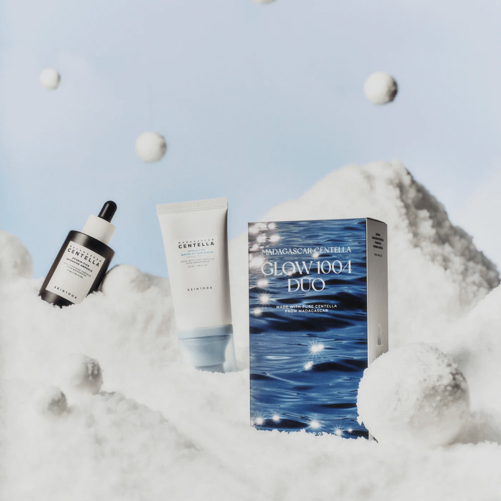 Das Bild zeigt das Hautpflegeset "Madagascar Centella Glow 1004 Duo" von SKIN1004, platziert vor einem Hintergrund, der Schnee und Himmel darstellt.