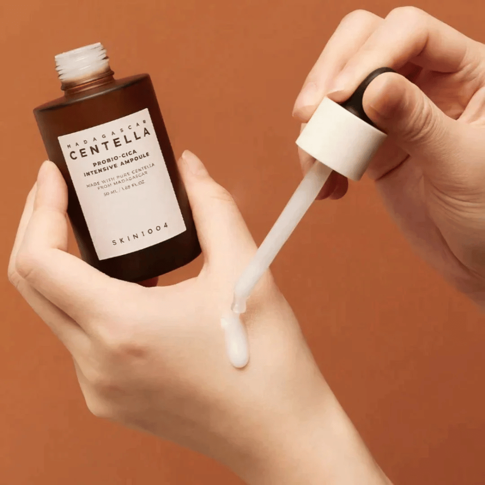 Hände, die eine Tropfpipette verwenden, um "Madagascar Centella Probio-Cica Intensive Ampoule" von SKIN1004 zu dosieren.