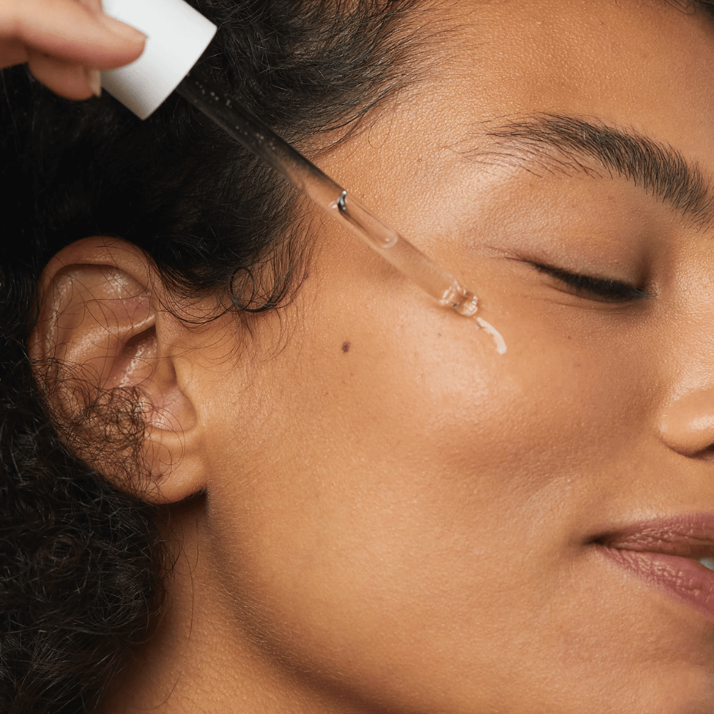Frau trägt Skin1004 Madagascar Centella Hyalu-Cica First Ampoule mit einer Pipette auf die Wange auf.