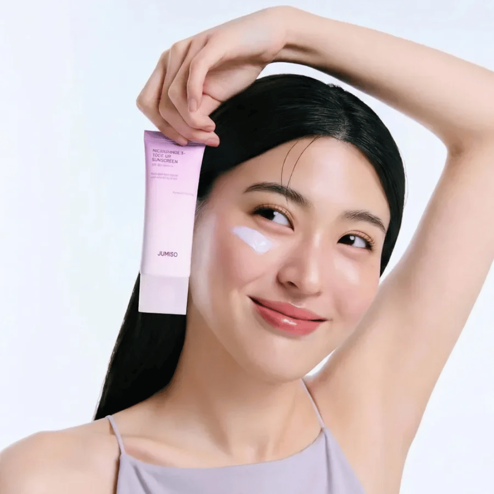 Das Model hält JUMISO Niacinamide 3+ Tone-Up Sunscreen SPF50+ PA++++ – Sonnencreme mit Niacinamid, die den Hautton ausgleicht und die Haut schützt.