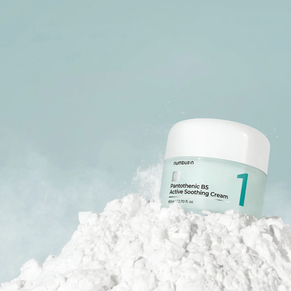 Numbuzin No.1 Pantothenic B5 Active Soothing Cream 80 ml i ljusgrön burk med vit lock, placerad på en hög av vitt pulver mot ljus bakgrund.