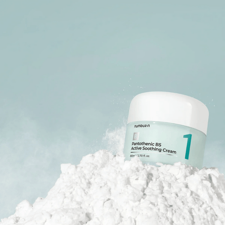 Numbuzin No.1 Pantothenic B5 Active Soothing Cream 80 ml i ljusgrön burk med vit lock, placerad på en hög av vitt pulver mot ljus bakgrund.