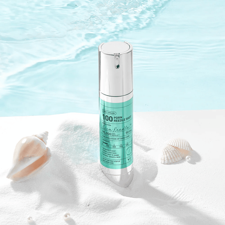 VT Cosmetics PDRN Reedle Shot 100 Produkt in einer Sandumgebung mit Meeresthema platziert, das Feuchtigkeitsversorgung, beruhigende Wirkung und Hautverbesserung symbolisiert