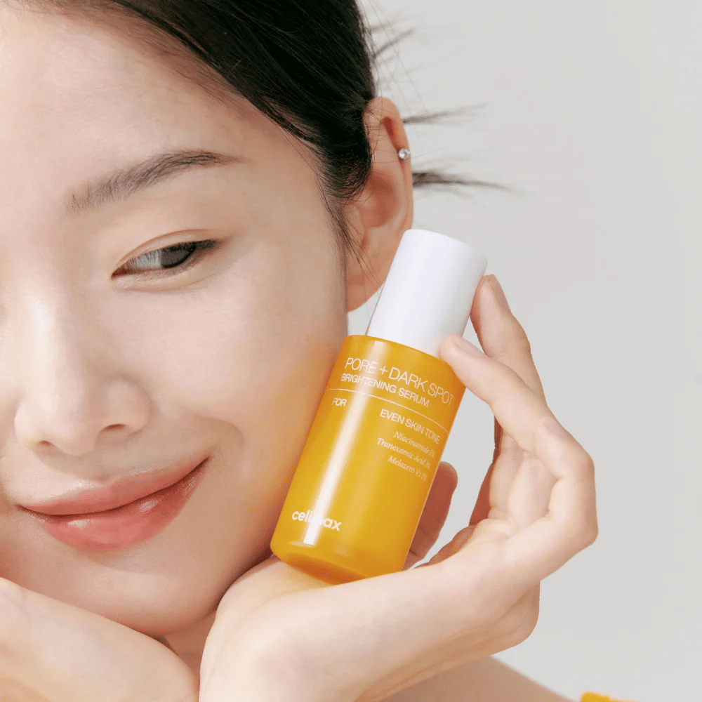 Modell hält Celimax Pore + Dark Spot Brightening Serum nahe am Gesicht, zeigt strahlende Haut.