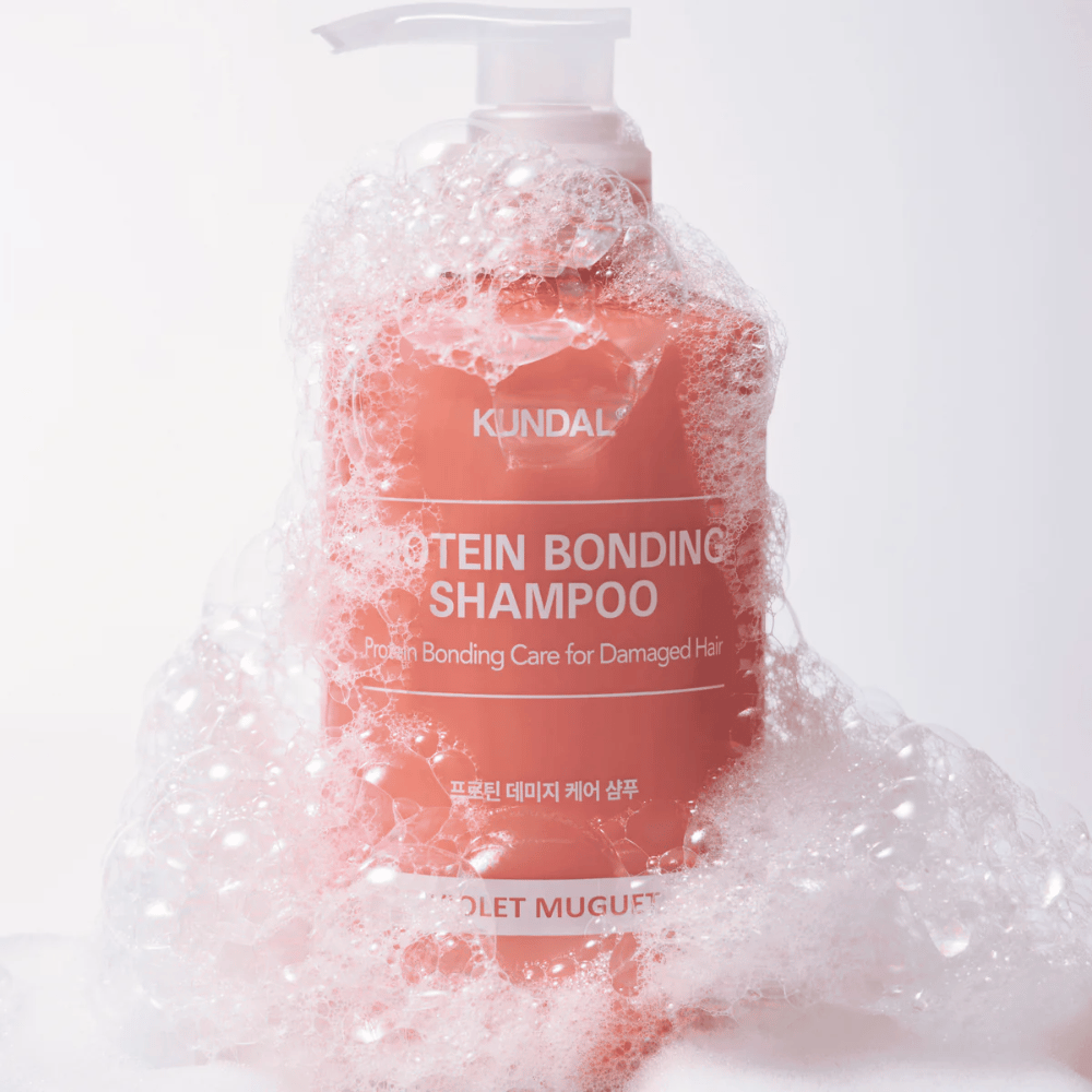 KUNDAL Protein Bonding Shampoo Violet Muguet bedeckt von reichlich Schaum, reparierendes Shampoo für geschädigtes Haar.