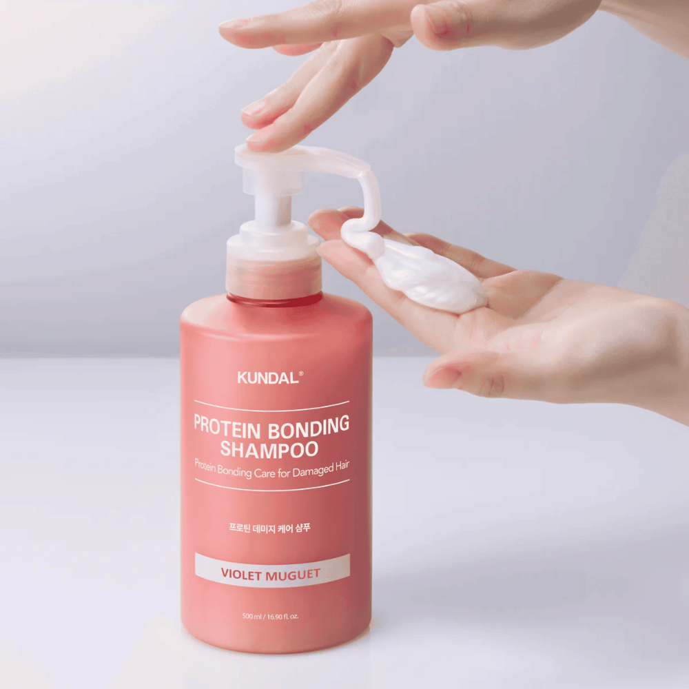 Hand pumpar ut KUNDAL Protein Bonding Shampoo Violet Muguet i krämig konsistens, reparerande schampo för skadat hår.