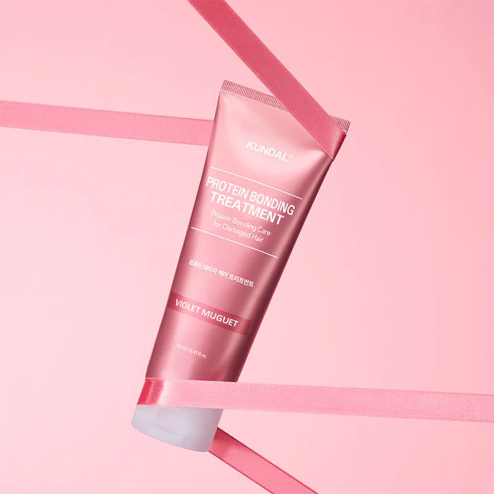 KUNDAL Protein Bonding Treatment Violet Muguet in rosa Tube 250 ml vor rosa Hintergrund mit dekorativen Bändern.