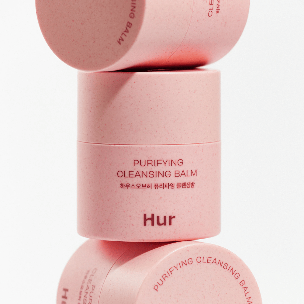 Wie Purifying Cleansing Balm in rosa Verpackung im Studio gestapelt. Reinigender Balsam, der effektiv Make-up, Talg und Unreinheiten auflöst, ohne die Haut auszutrocknen.