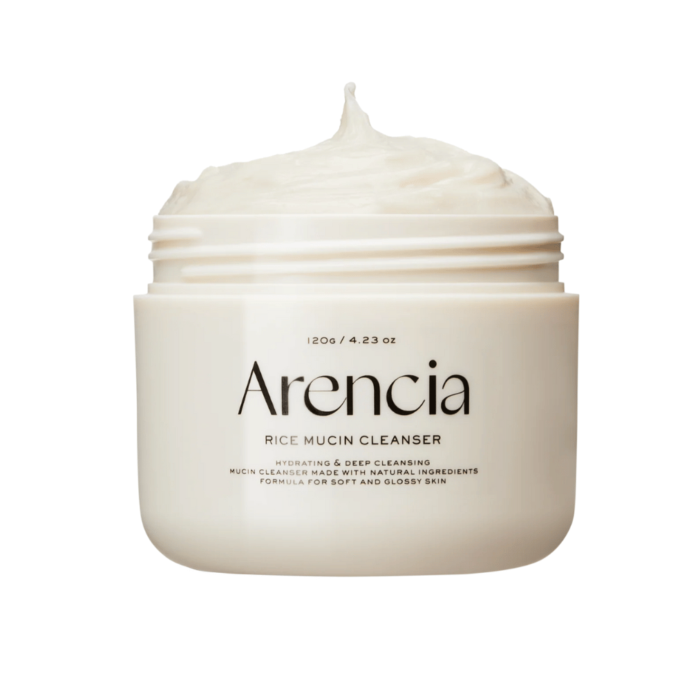 Produktbild von Arencia Rice Mucin Cleanser in einem weißen Behälter mit cremiger, aufgeschlagener Textur, die aus der Öffnung hervorragt. Der Text auf der Verpackung betont Feuchtigkeitspflege und Tiefenreinigung.