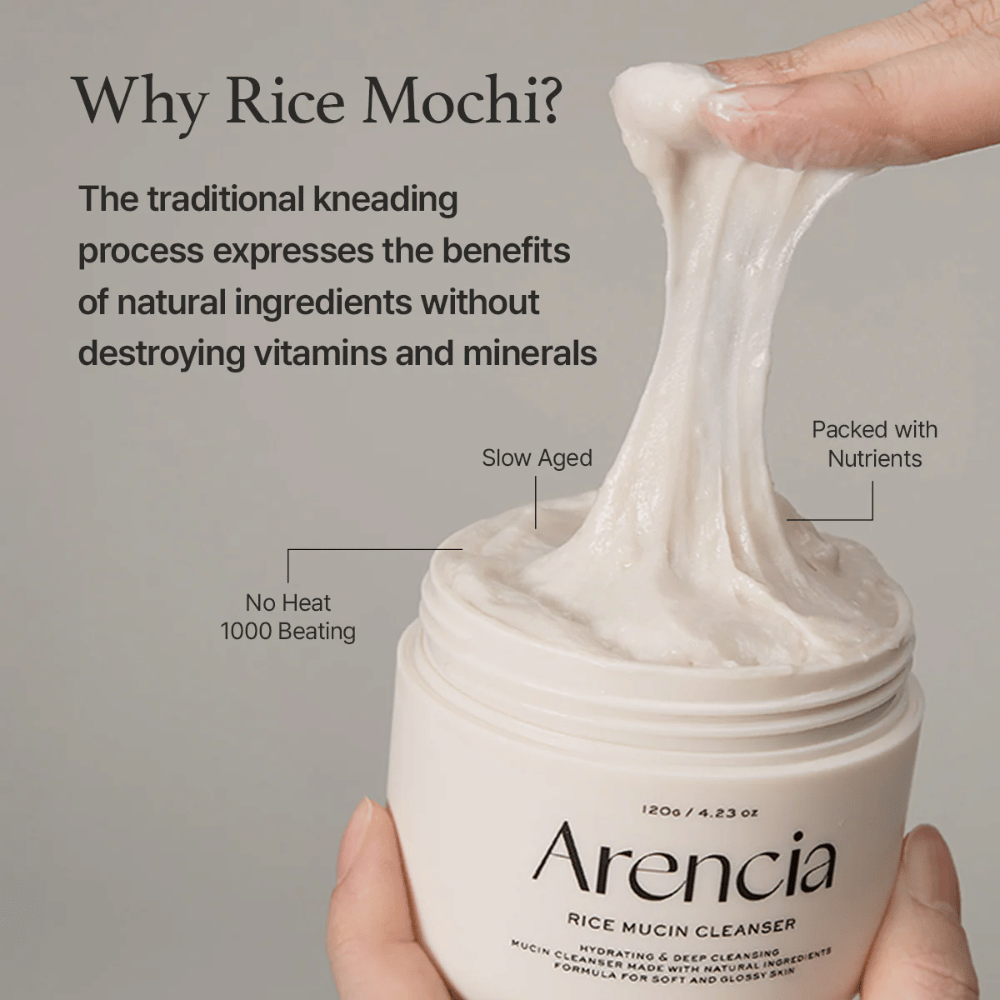 Hand, die eine elastische, weiße Reinigungscreme aus einem Behälter hebt, der mit "Arencia Rice Mucin Cleanser" gekennzeichnet ist. Der Text beschreibt traditionelle Knetung, die Nährstoffe bewahrt, ohne Vitamine und Mineralien zu zerstören.