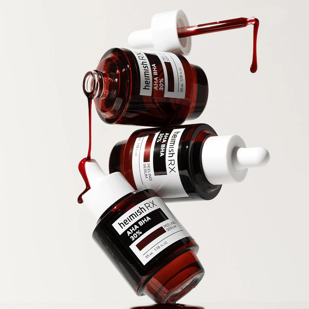 Drei Flaschen Heimish RX AHA BHA 30% Peeling-Serum in einer dynamischen Komposition, mit rot gefärbtem Serum, das von den Pipetten tropft.