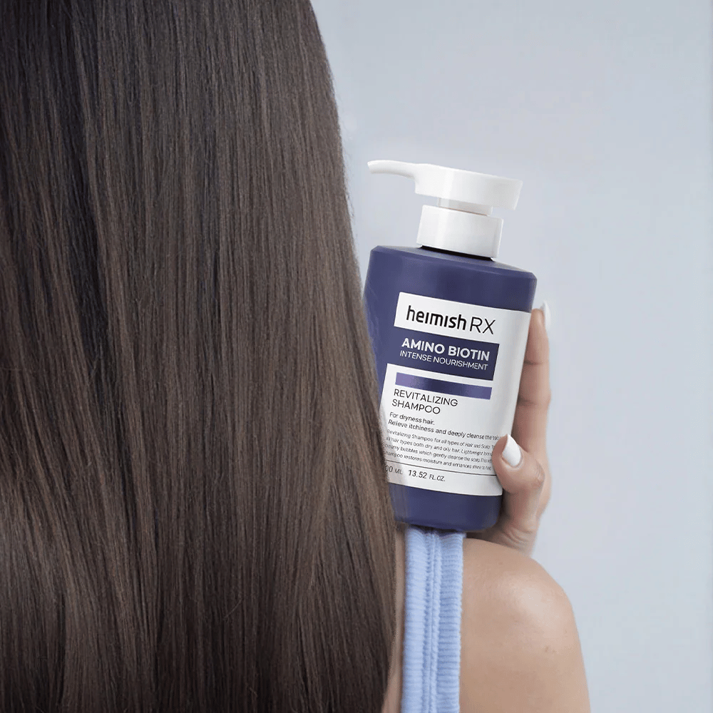Heimish RX Amino Biotin Revitalizing Shampoo wird in der Hand gehalten gegen langes, glänzendes Haar – zeigt das Ergebnis intensiver Ernährung und Befeuchtung für trockenes Haar.