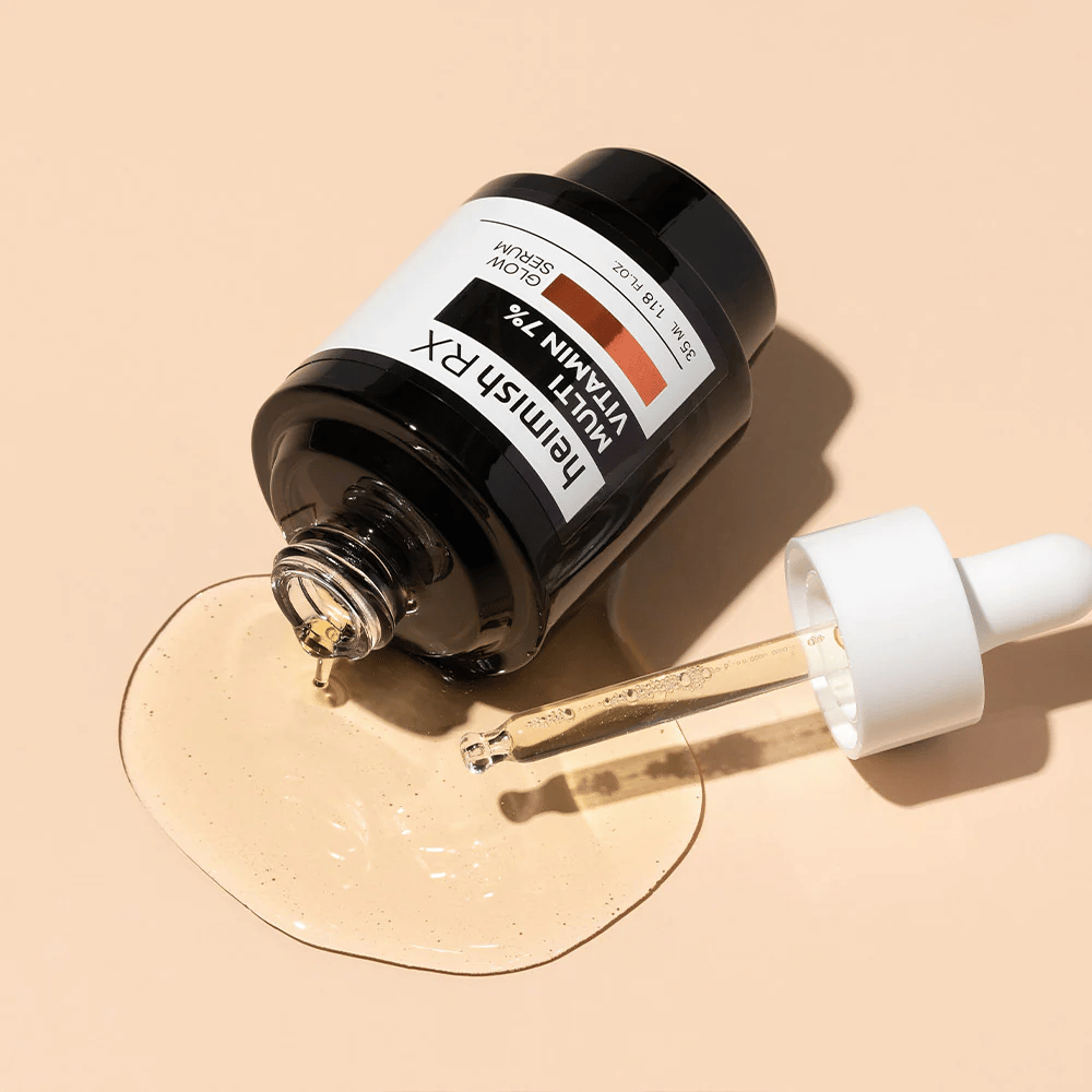 Heimish RX Multi Vitamin 7% Glow Serum auf einem beigen Hintergrund liegend mit um die Flasche verteiltem Serum und einer mit Produkt gefüllten Pipette, die seine nährstoffreiche Formel hervorhebt.